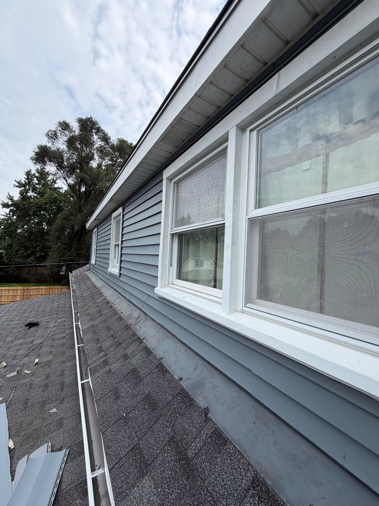 New gutters and gray lap siding along a roofline
