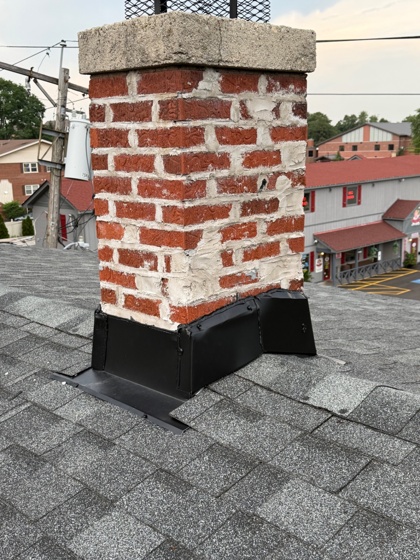 New black chimney flashing installed on a fresh asphalt shingle roof