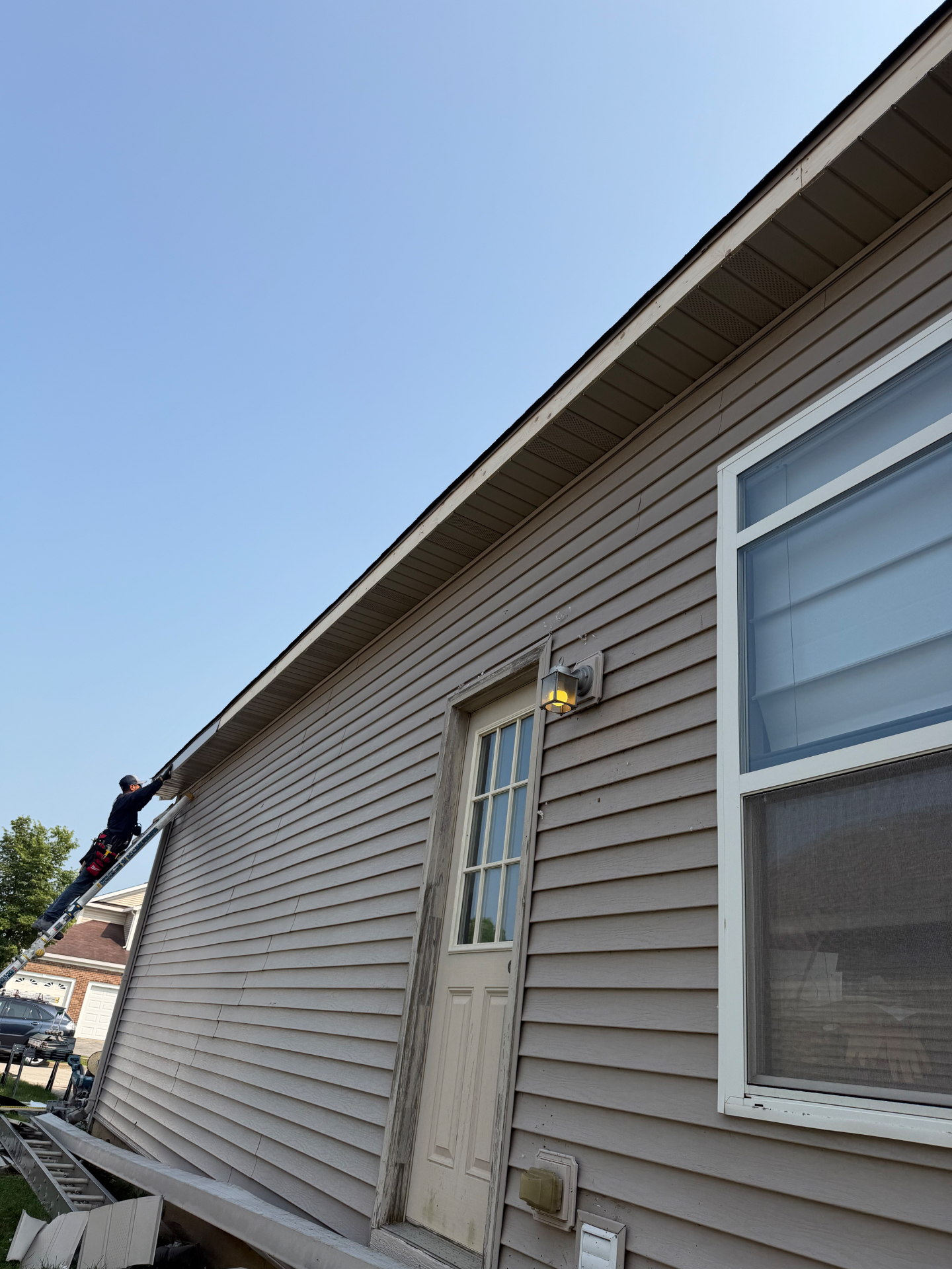 Frontline Restoration crew member on a ladder installing soffit and fascia trim